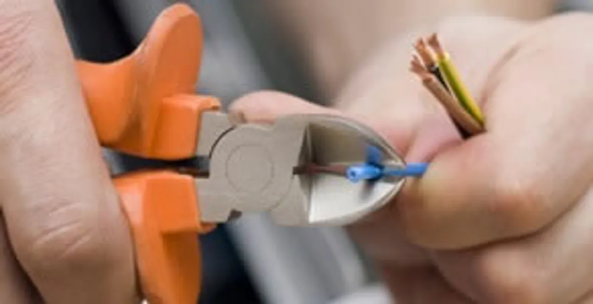 licensed electrician performing precise wire cutting and preparation during electrical service in Grand Rapids, MI